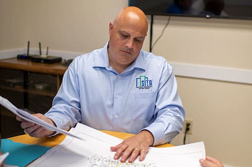 Brian Kaupp reading building plans in his office