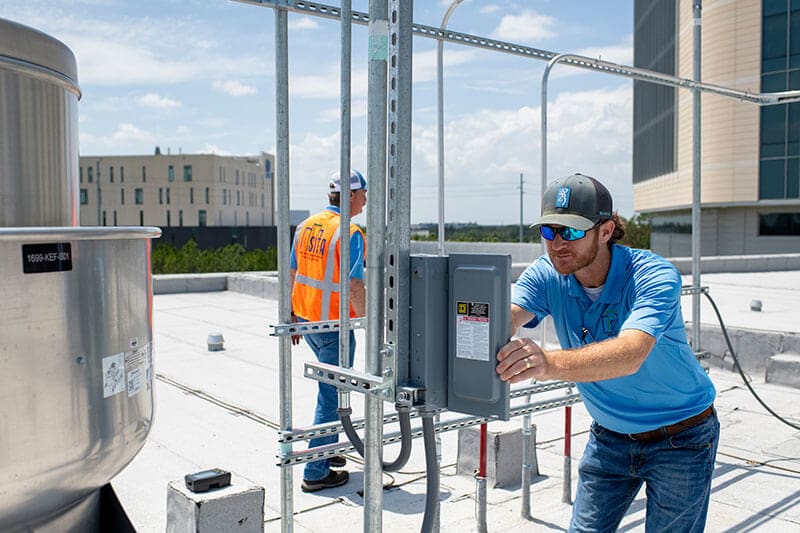 Two men are busy working on a rooftop on building HVAC Commissioning