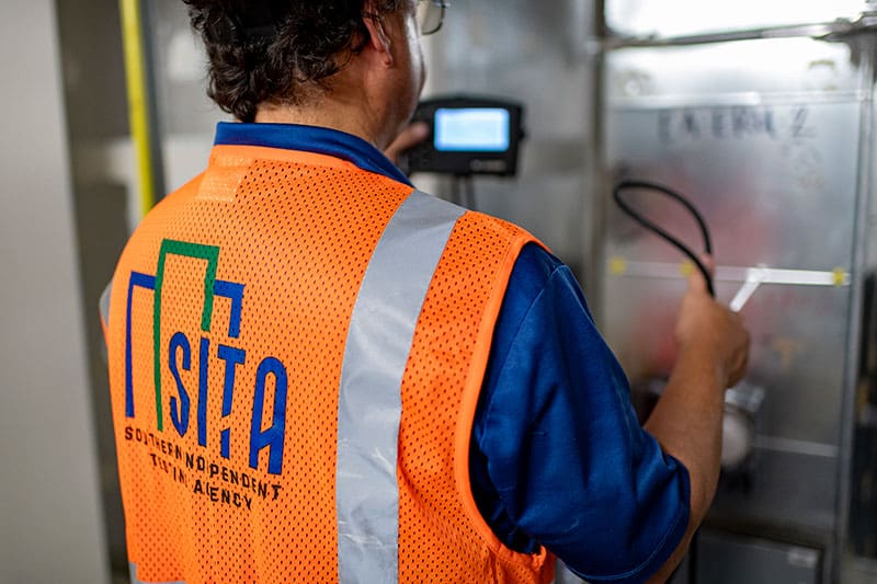 A man with a SITA reflective vest is busy with building the HVAC testing