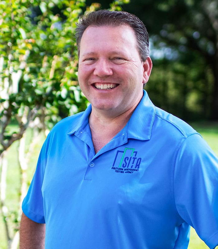 Keith w Bunner from SITA, outdoors posing and smiling in his blue SITA golfer 2