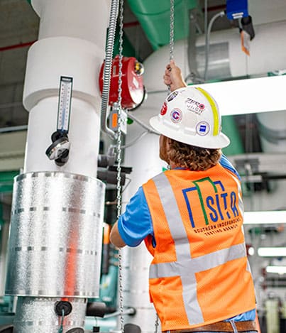 a SITA technical employee wearing his reflective top, Pulls down a chain for one of the onsite Air guages