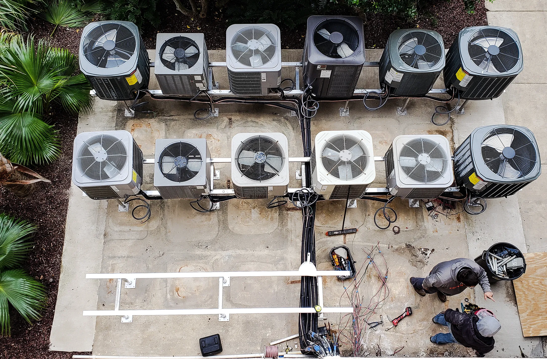 Maintenance men working to get all the condo air conditioners off the ground to slow rust buildup.