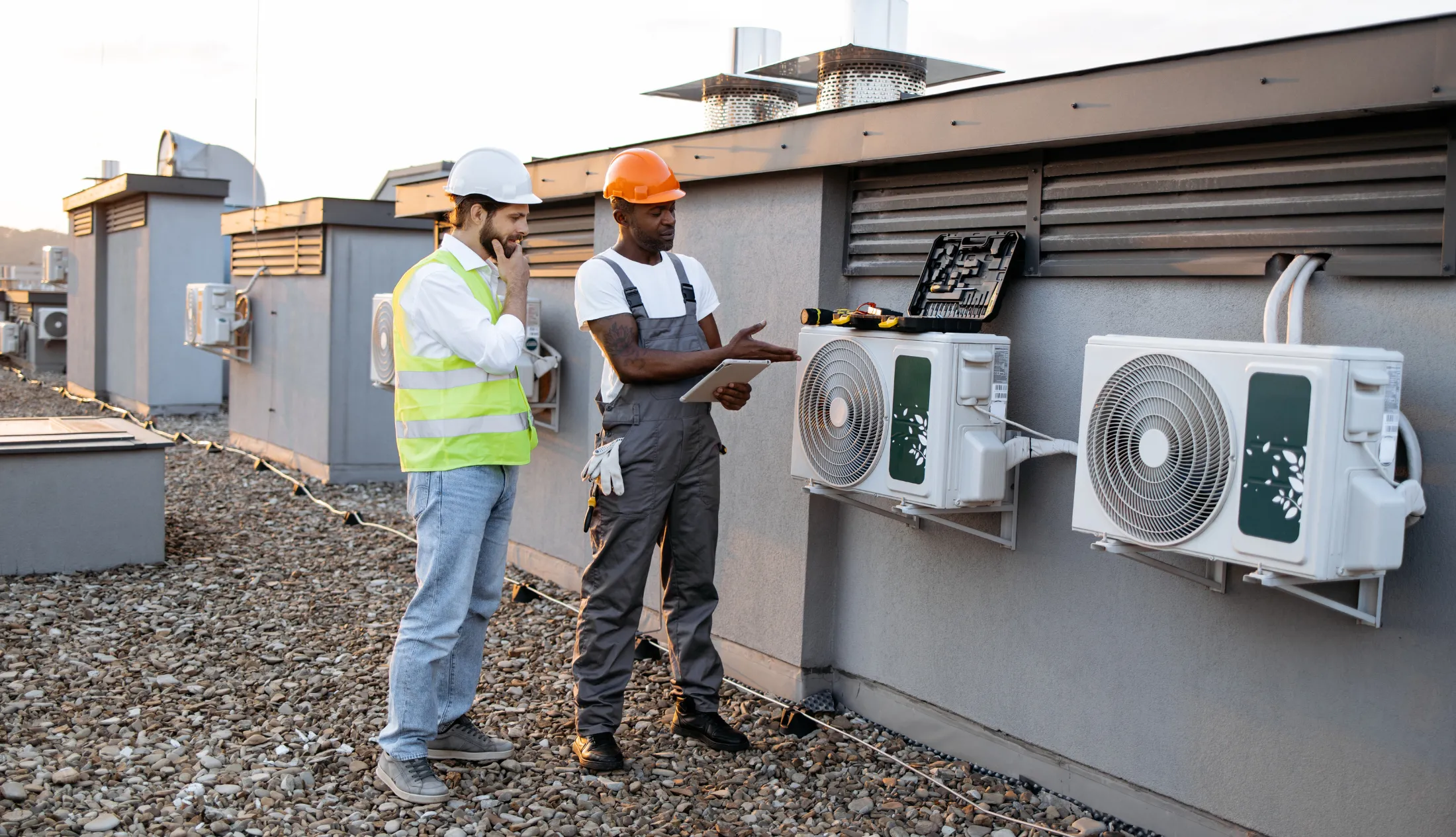 Blog-Cover-Images2200-x-1265-px-23 Technicians conducting rooftop HVAC equipment inspection, discussing system performance and ensuring compliance with building standards and energy efficiency goals.