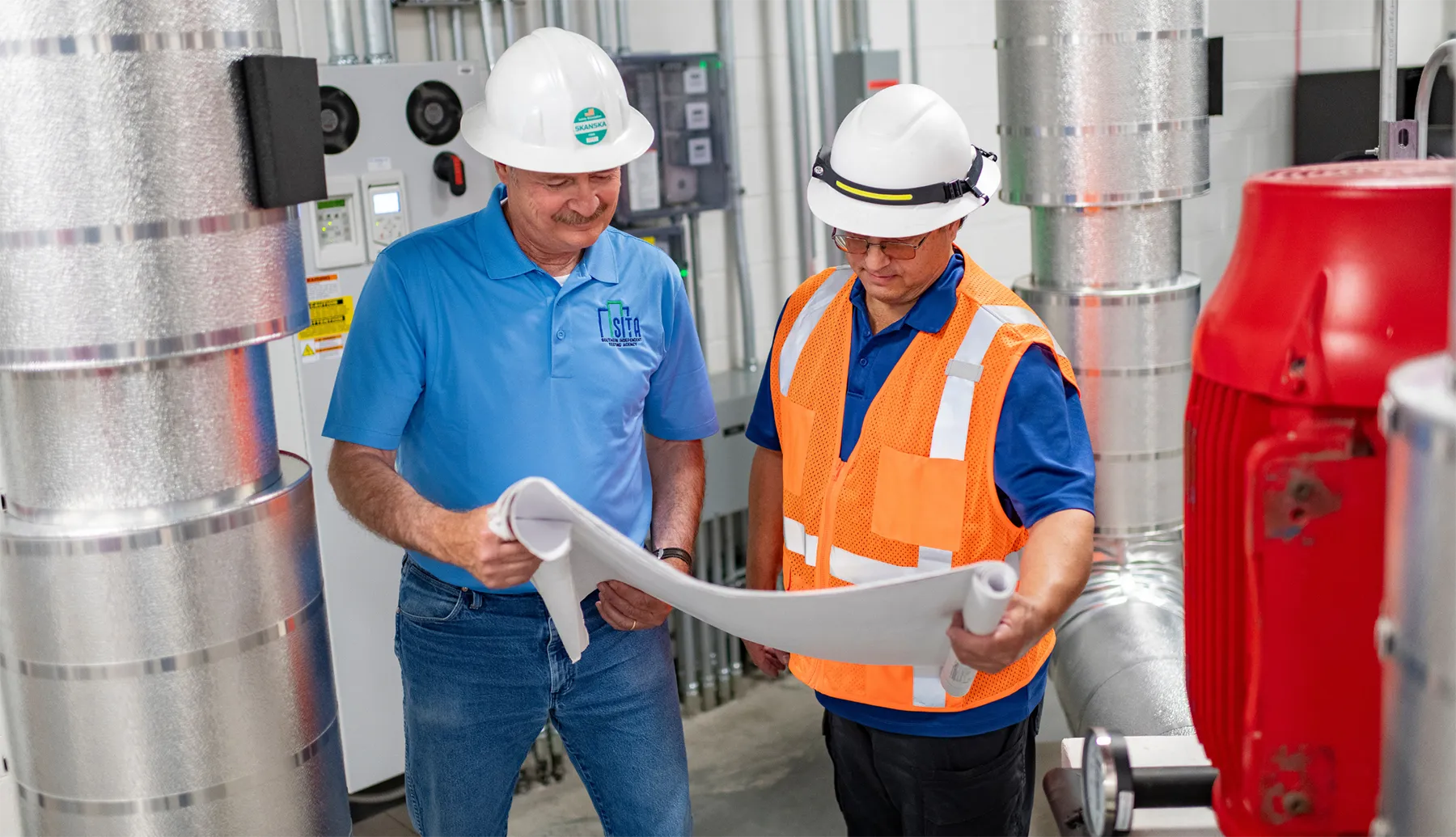 Blog-Cover-Images2200-x-1265-px-29 HVAC technicians reviewing mechanical plans during a building commissioning inspection, ensuring system efficiency and code compliance for optimal performance.