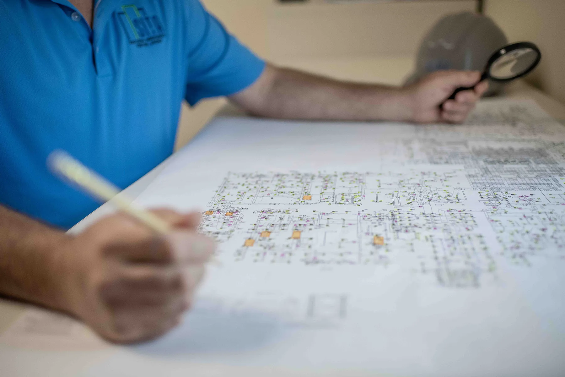 DSC_1293 Engineer reviewing detailed HVAC commissioning plans with a magnifying glass, ensuring air conditioning system design supports optimal energy efficiency.