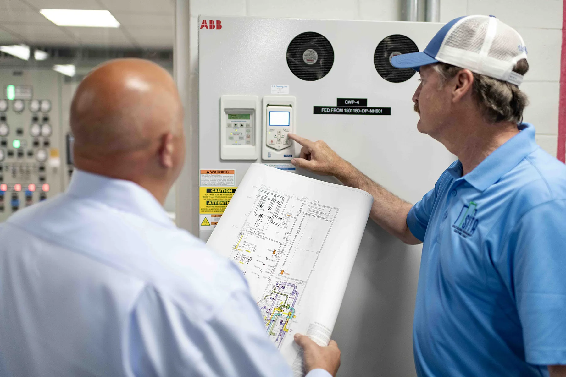 DSC_1719 Two professionals review HVAC schematics and control systems, highlighting air barrier testing and its impact on HVAC performance and building envelope integrity.
